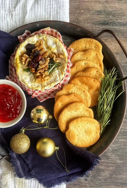 tray woth baked cheese on wooden board with crackers, rosemary and chilli jam