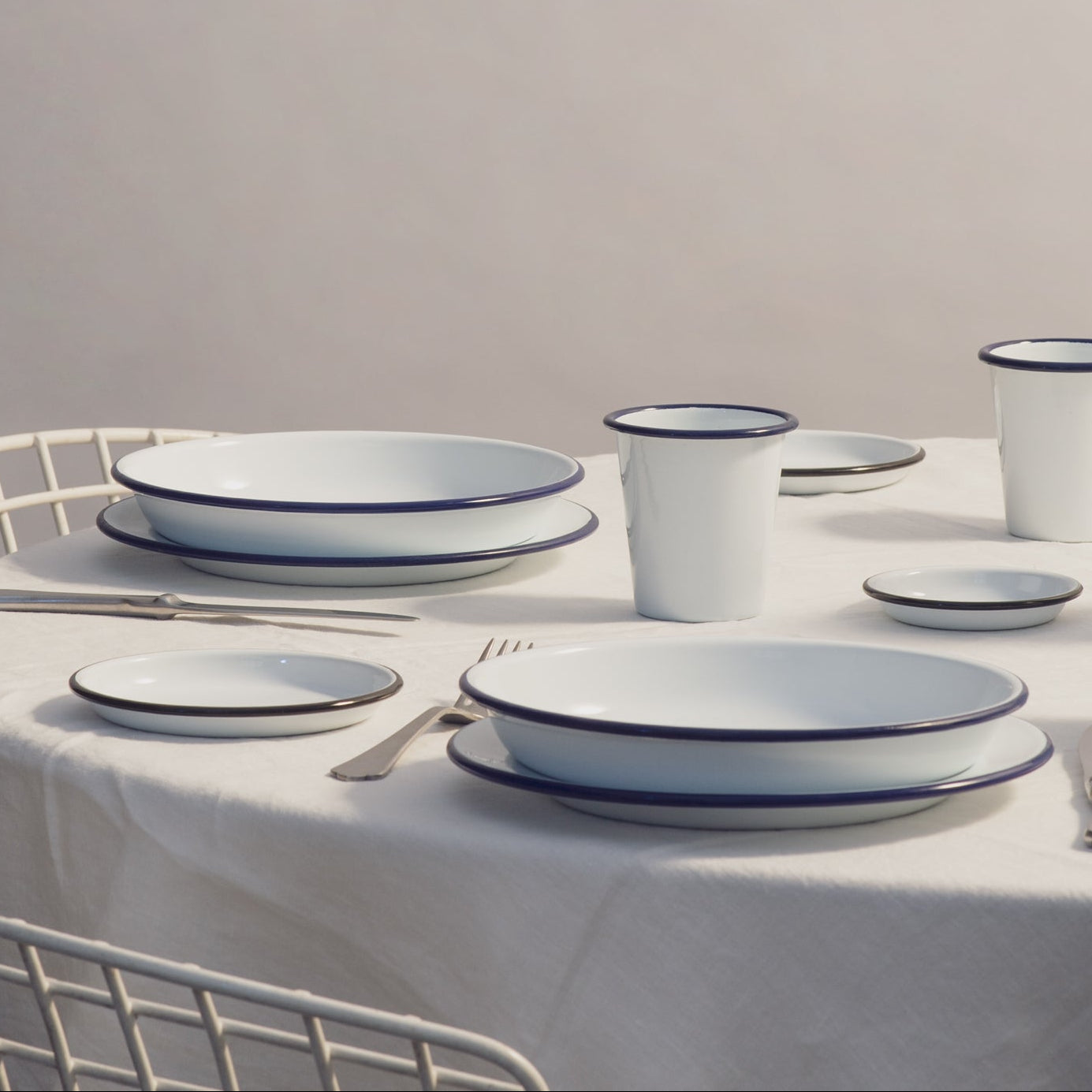 White ceramic tableware set on a round table with a neutral background