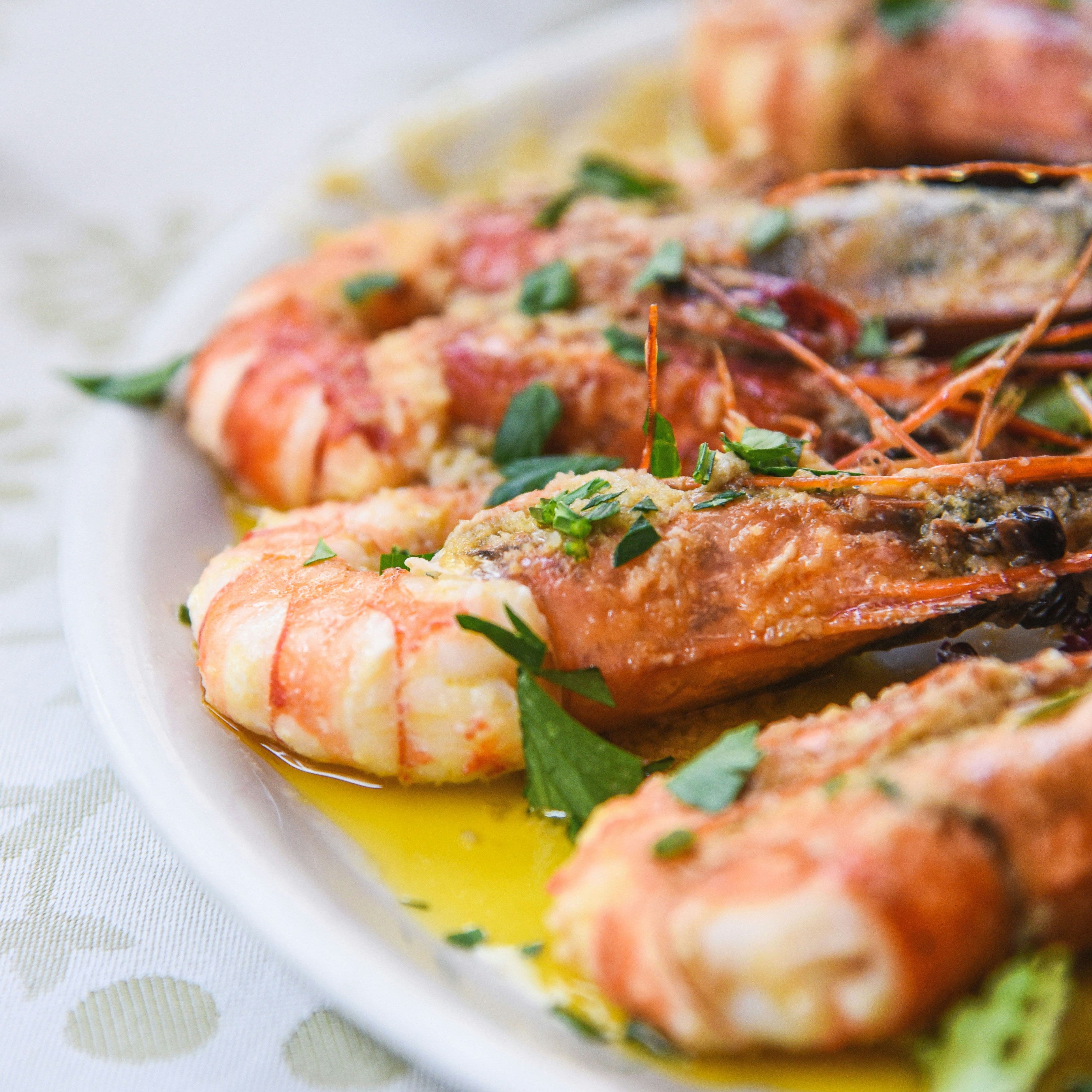 Platter of cooked prawns with herbs on a white plate