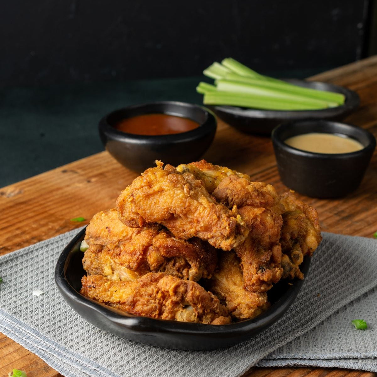fried chicken on a board with sauces and celery