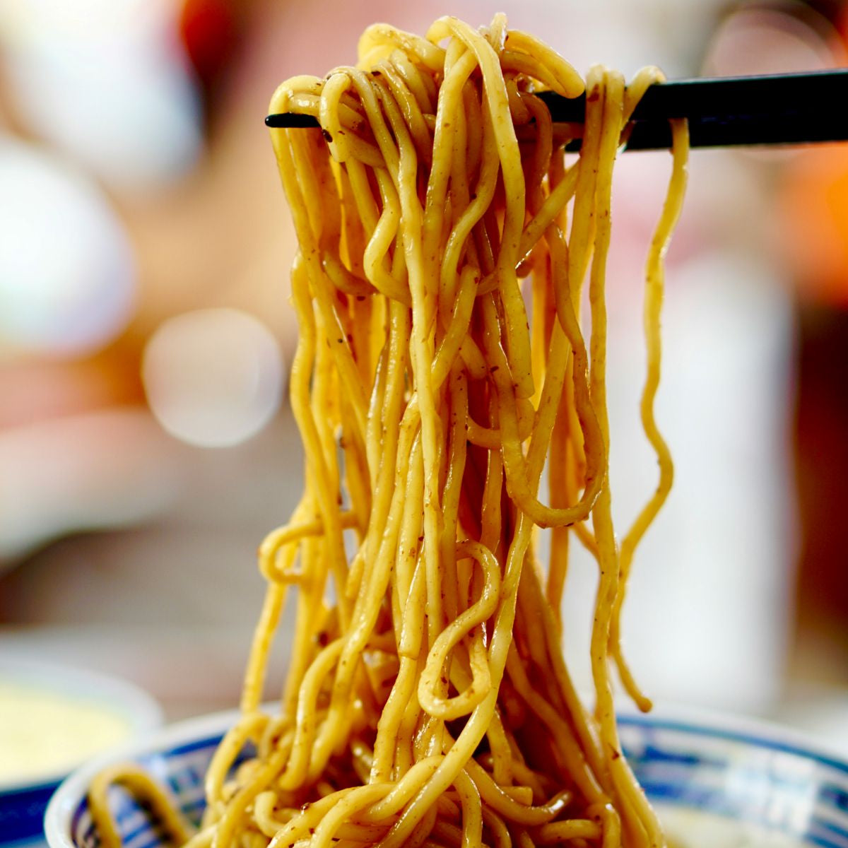 Noodles being lifted with chopsticks from a bowl
