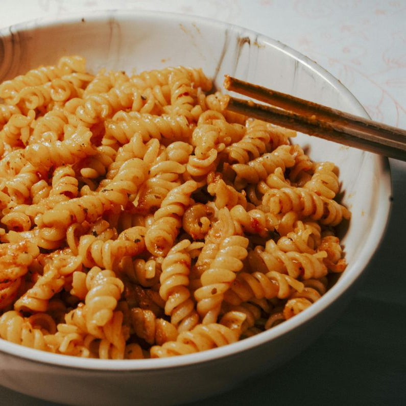 White bowl filled with spiral pasta on a light background