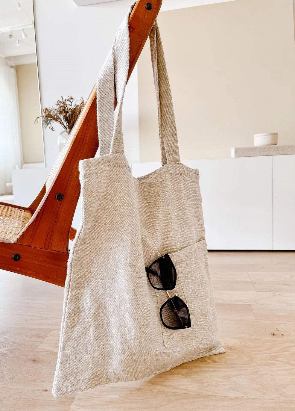 Beige tote bag with sunglasses on a wooden floor
